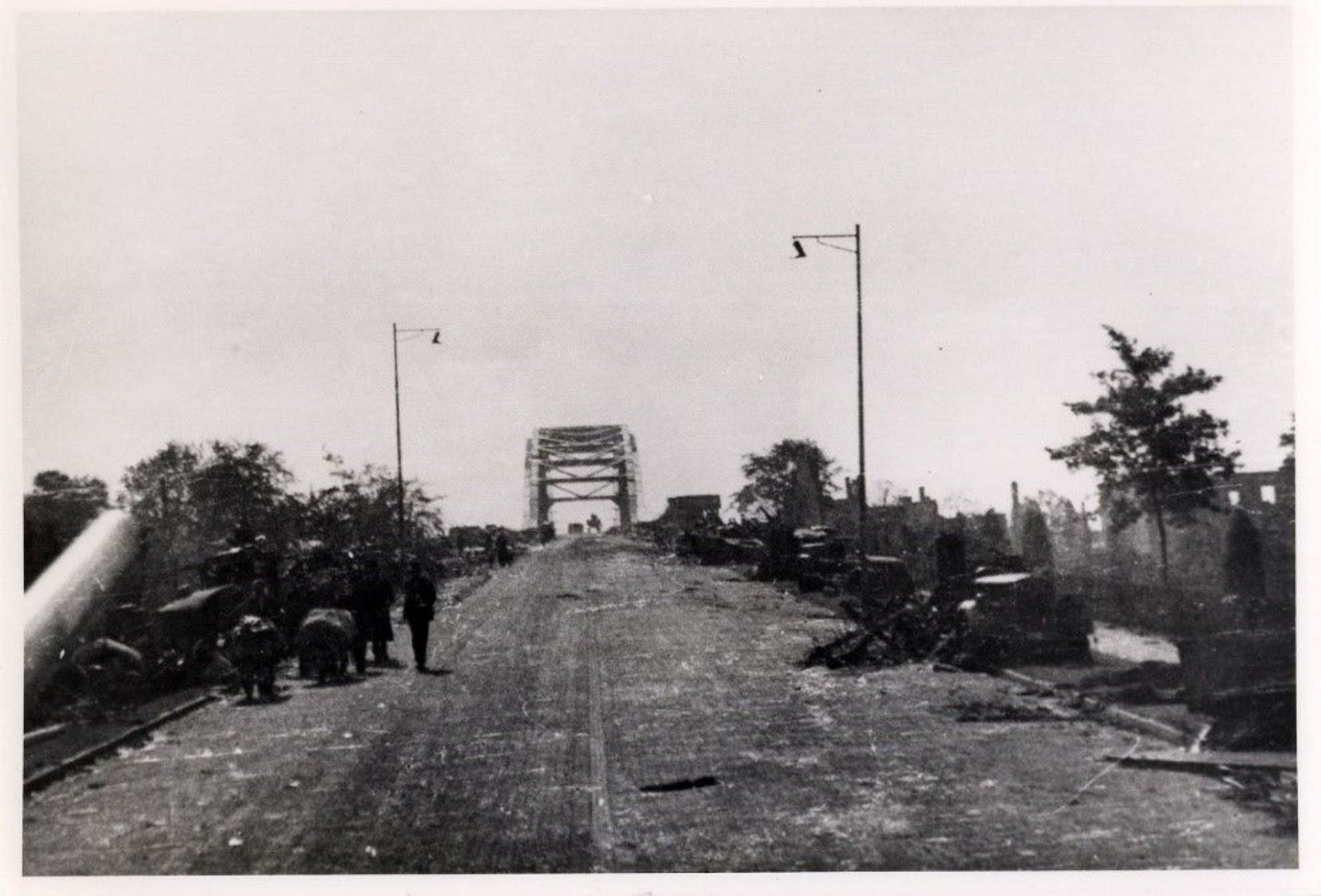 Foto van de Rijnbrug, nu de John Frostbrug in Arnhem. Er staan verwoeste gebouwen en voertuigen op. Ook inwoners van Arnhem die moeten vluchten.
